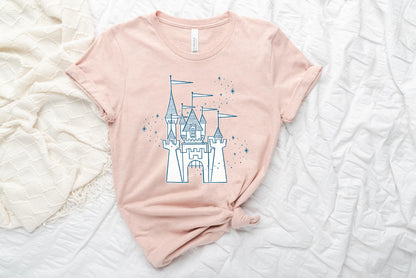 Light pink shirt printed with vintage style sketch of the Disneyland Castle and pixie dust above the castle. The shirt is set on two blankets.
